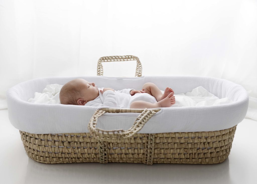 Newborn boy in white onesie sleeping in a Moses Basket by Fort Worth Newborn Photographer