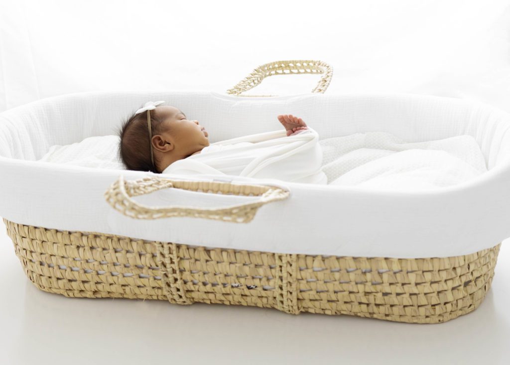 Newborn baby sleeping in Moses Basket