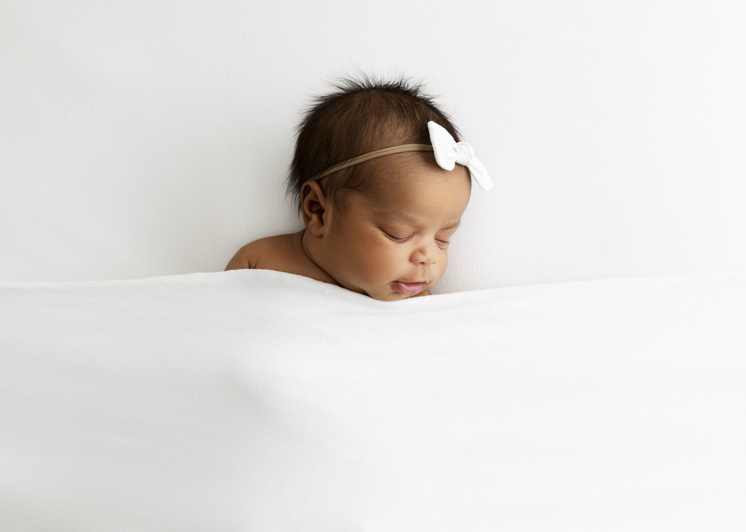 Newborn baby girl sleeping under white blanket for Dallas Prenatal Massage