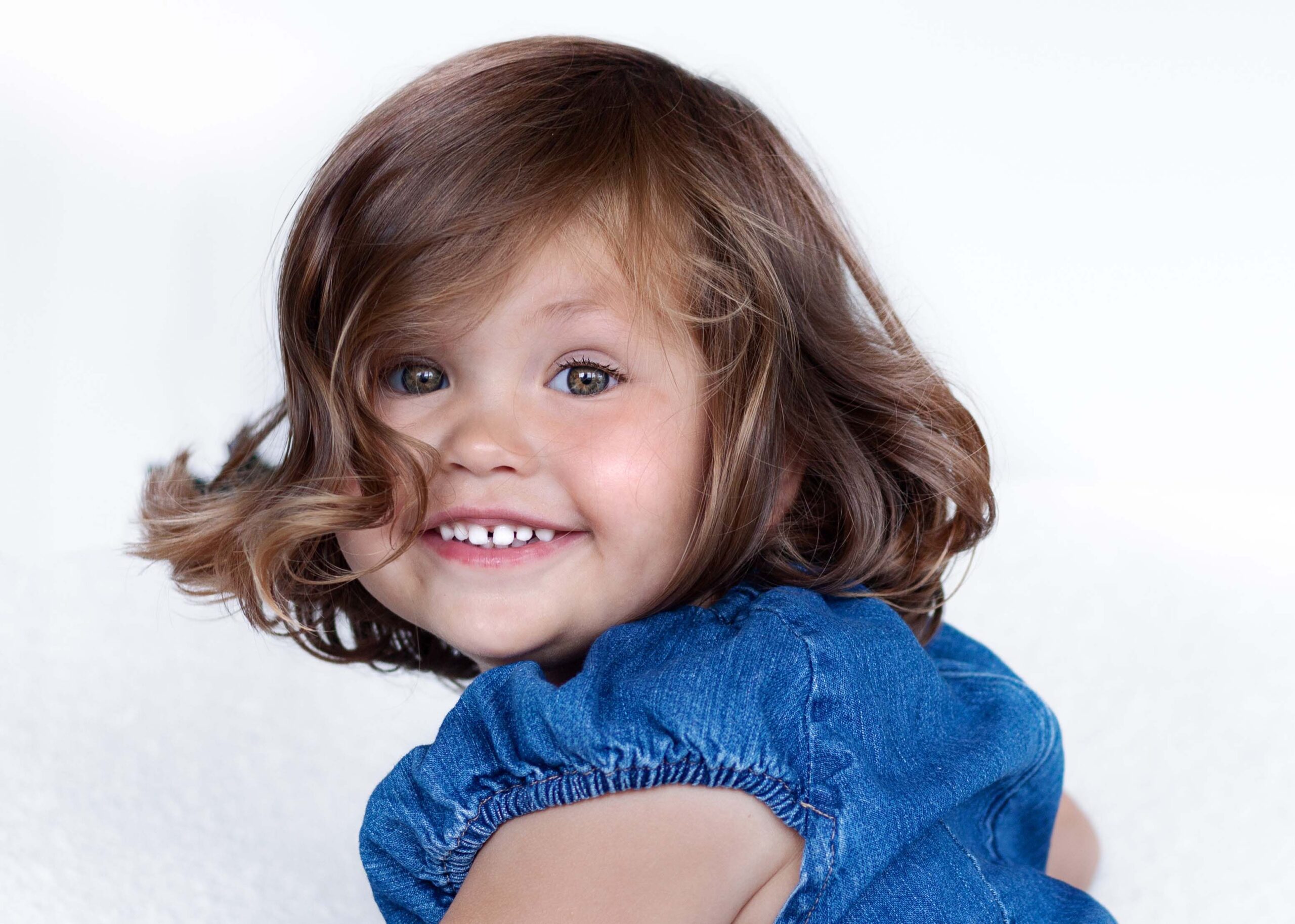 Little girl in denim dress turning around and smiling