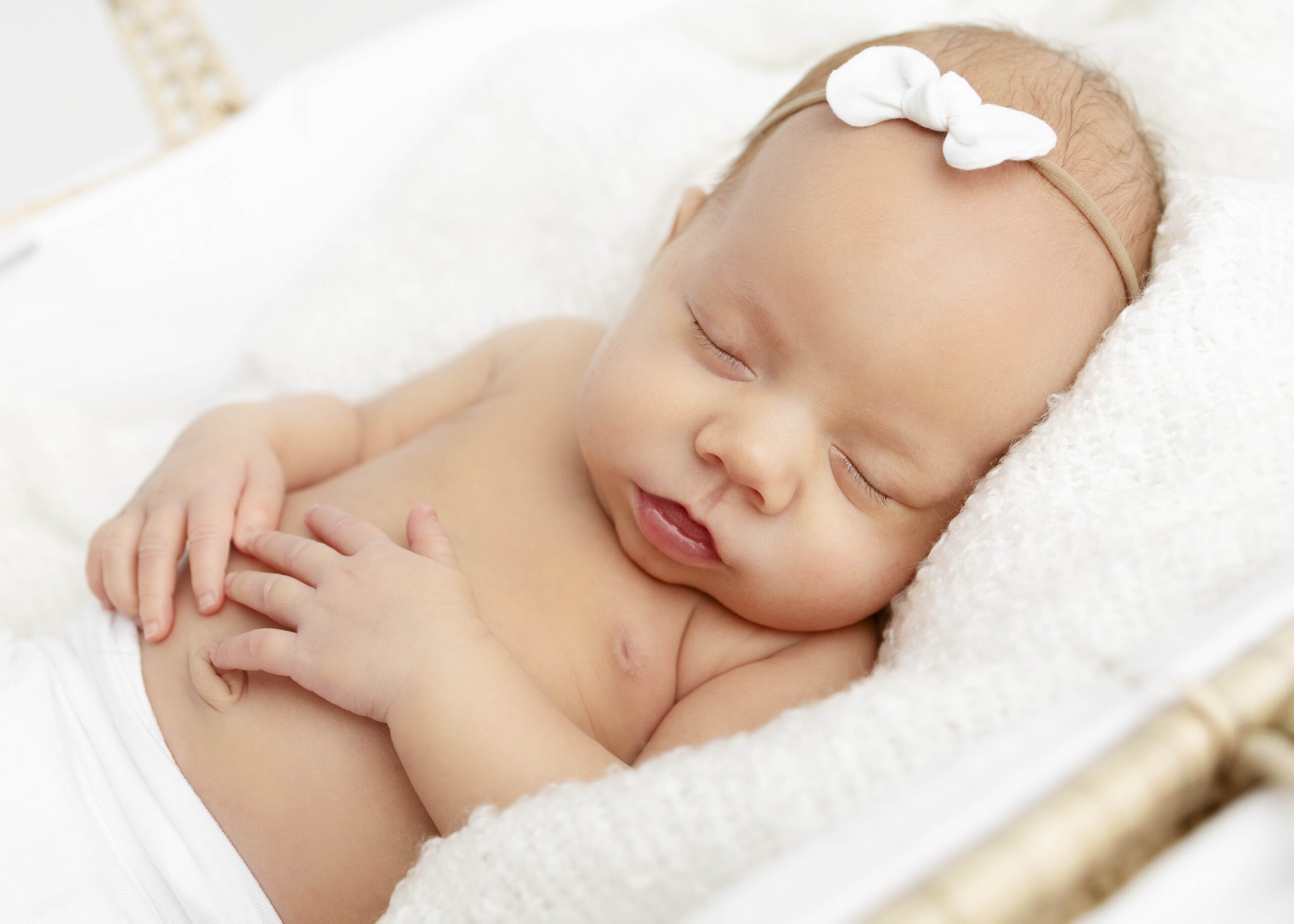 Newborn girl sleeping surrounded by fluffy white blankets