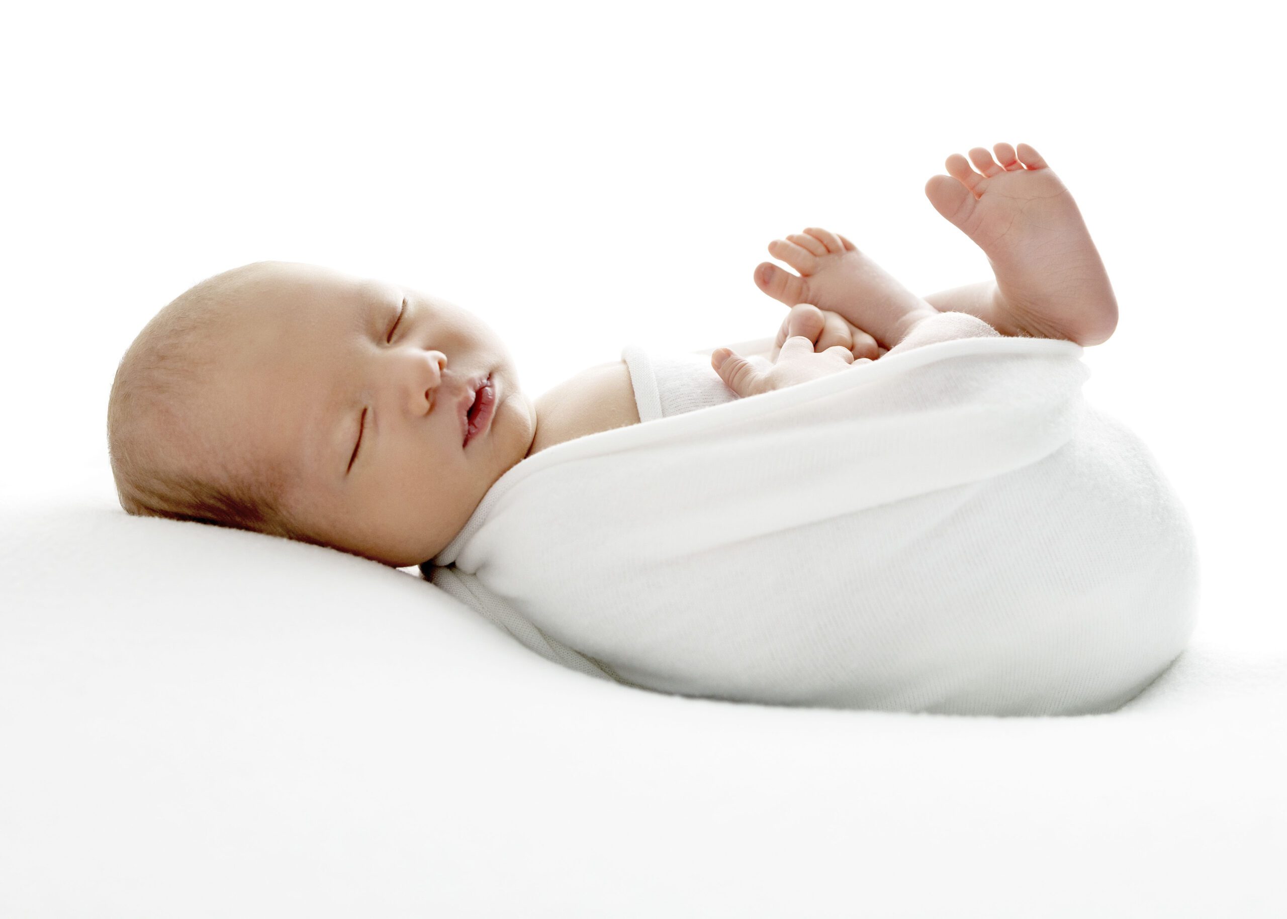 Newborn baby sleeping with white wrap around body and toes sticking up in the air