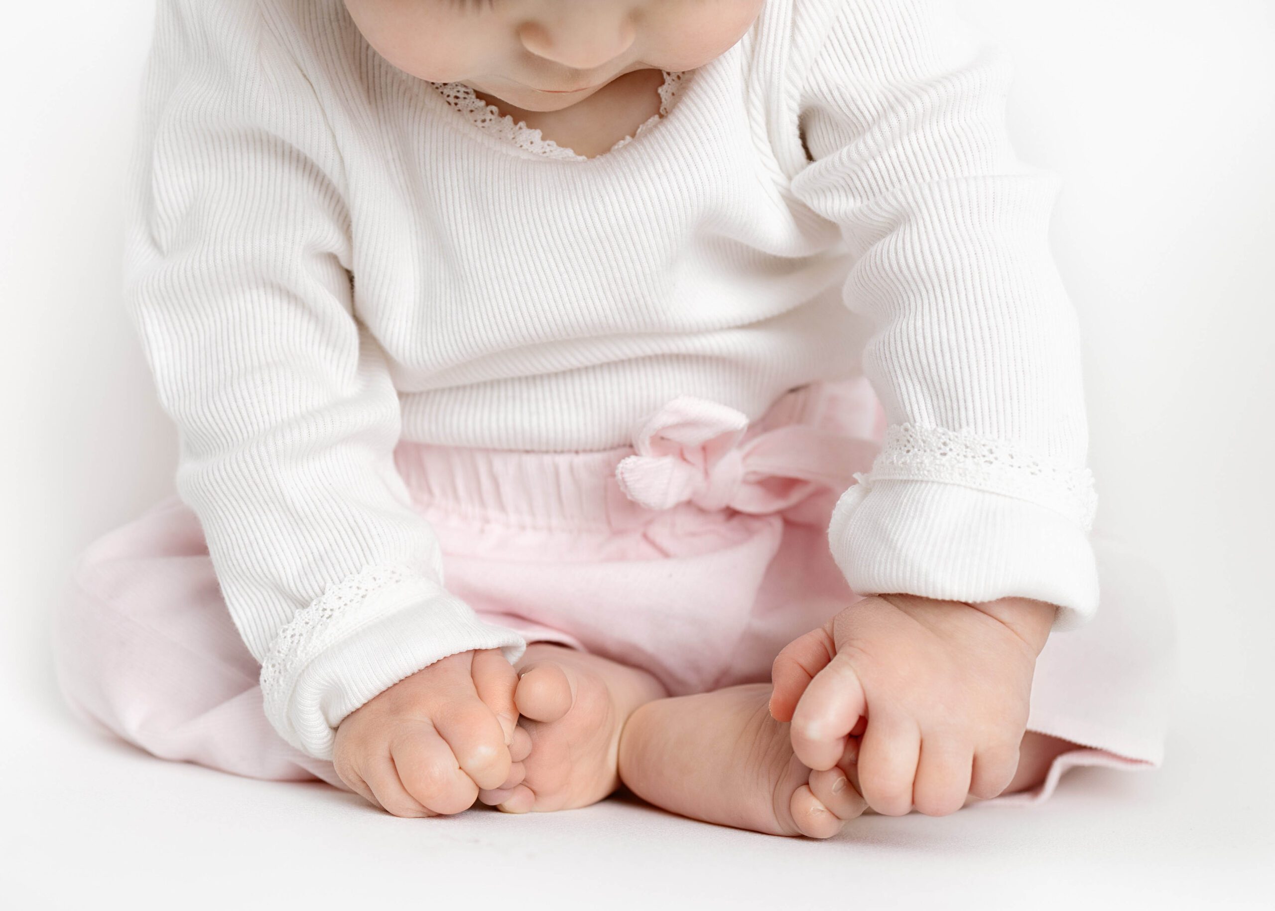 baby girl sitting and looking at her toes by baby photography dallas