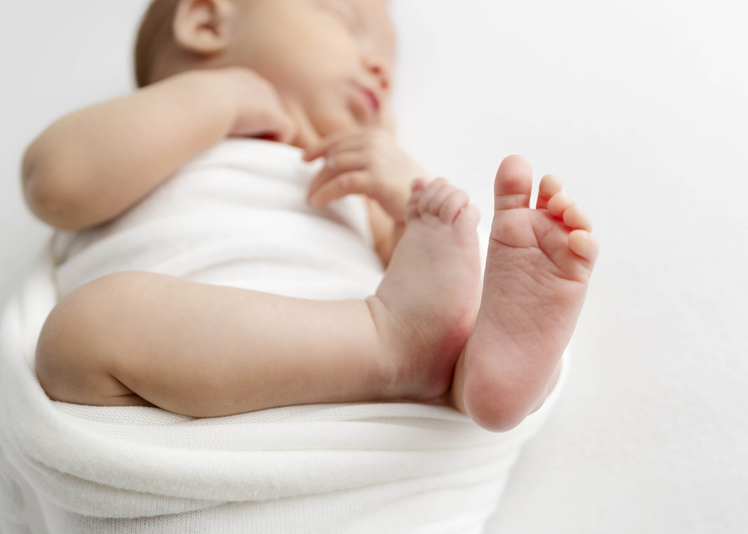 newborn baby sleeping with toes in focus and head blurred