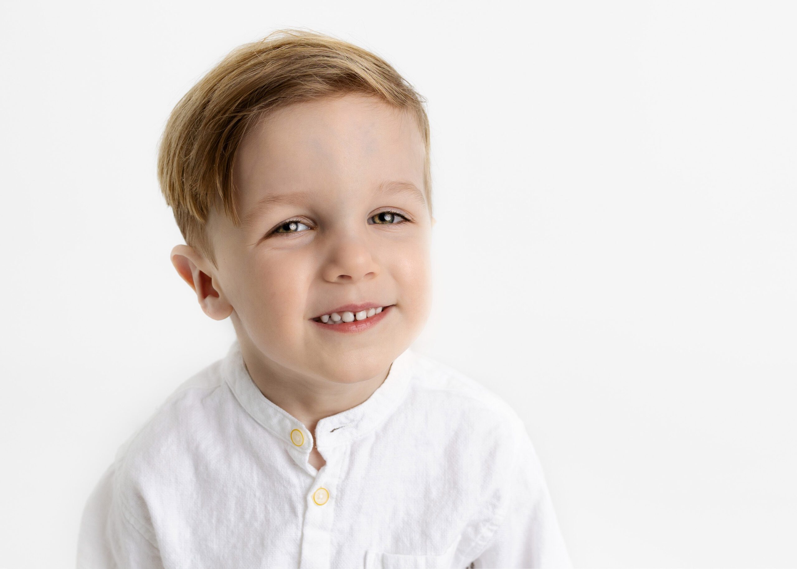 Toddler boy in white shirt smiling at the camera