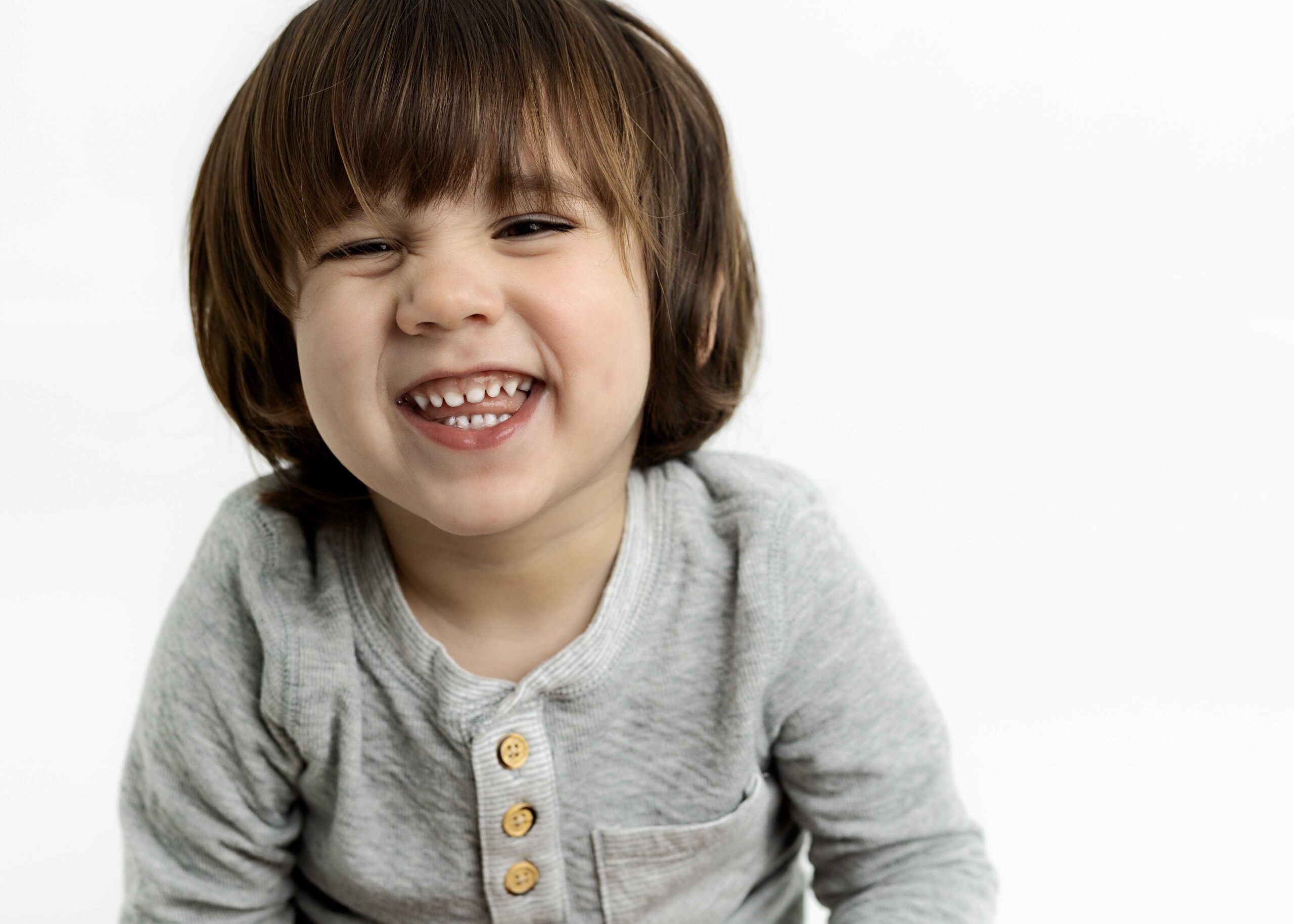 Toddler boy making a silly face at the camera by white studio photography