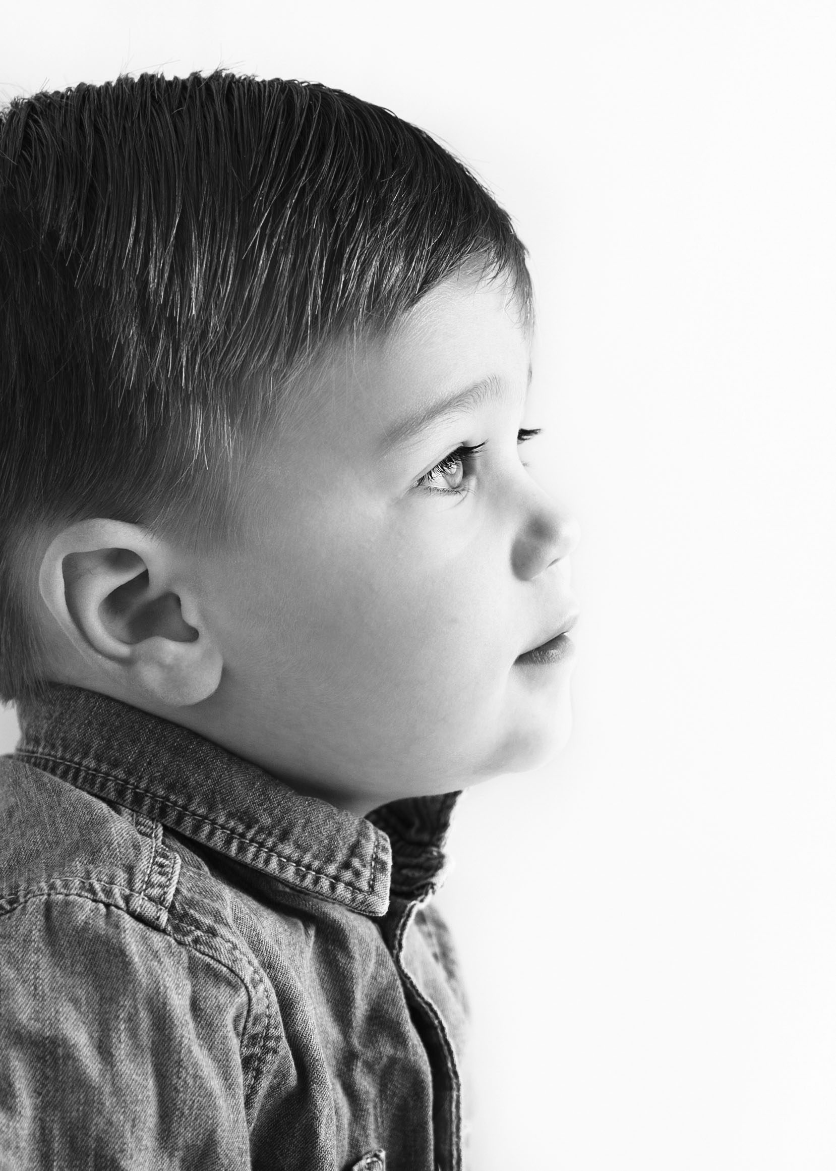 Close up profile in black and white of a toddler boy by white studio photography