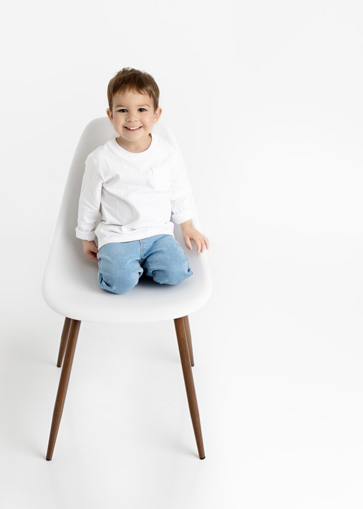 Toddler boy in white t-shirt and jeans sitting on chair
