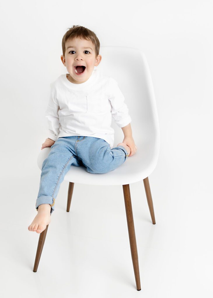 Toddler boy climbing off the chair with a surprised look on his face.