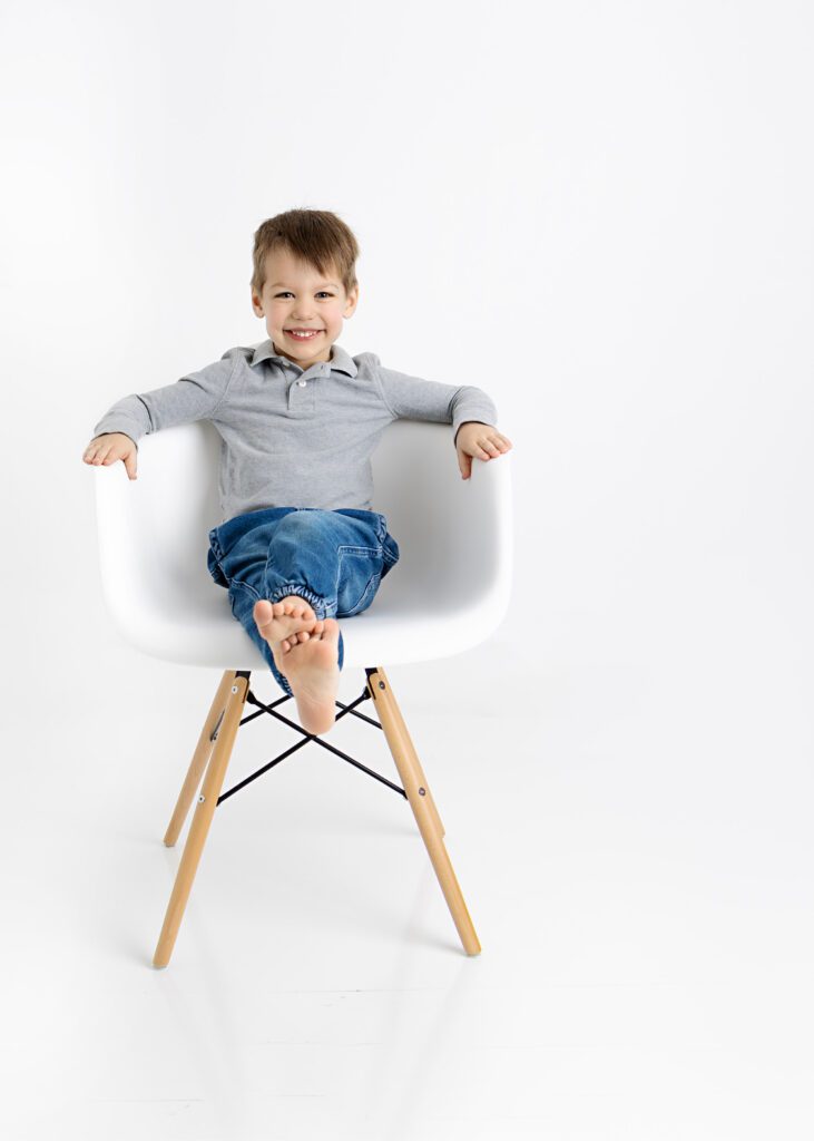 Young boy sitting on a chair looking very proud