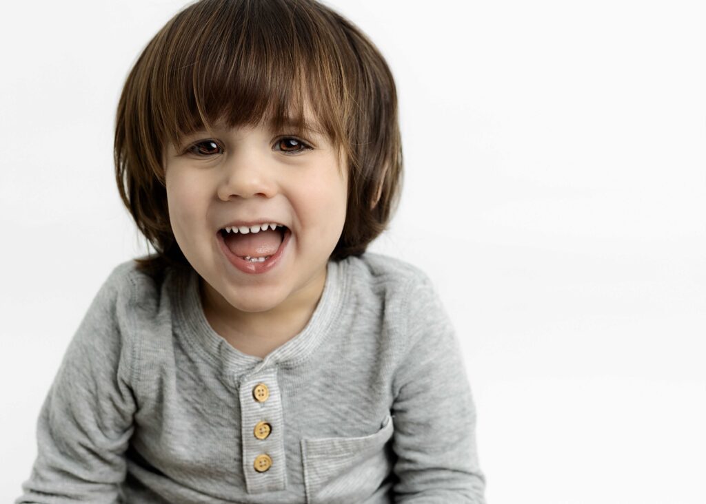 Toddler boy with open mouth smile at camera