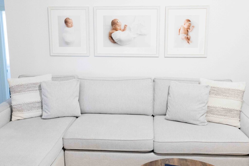 grey sofa with newborn framed pictures behind it.
