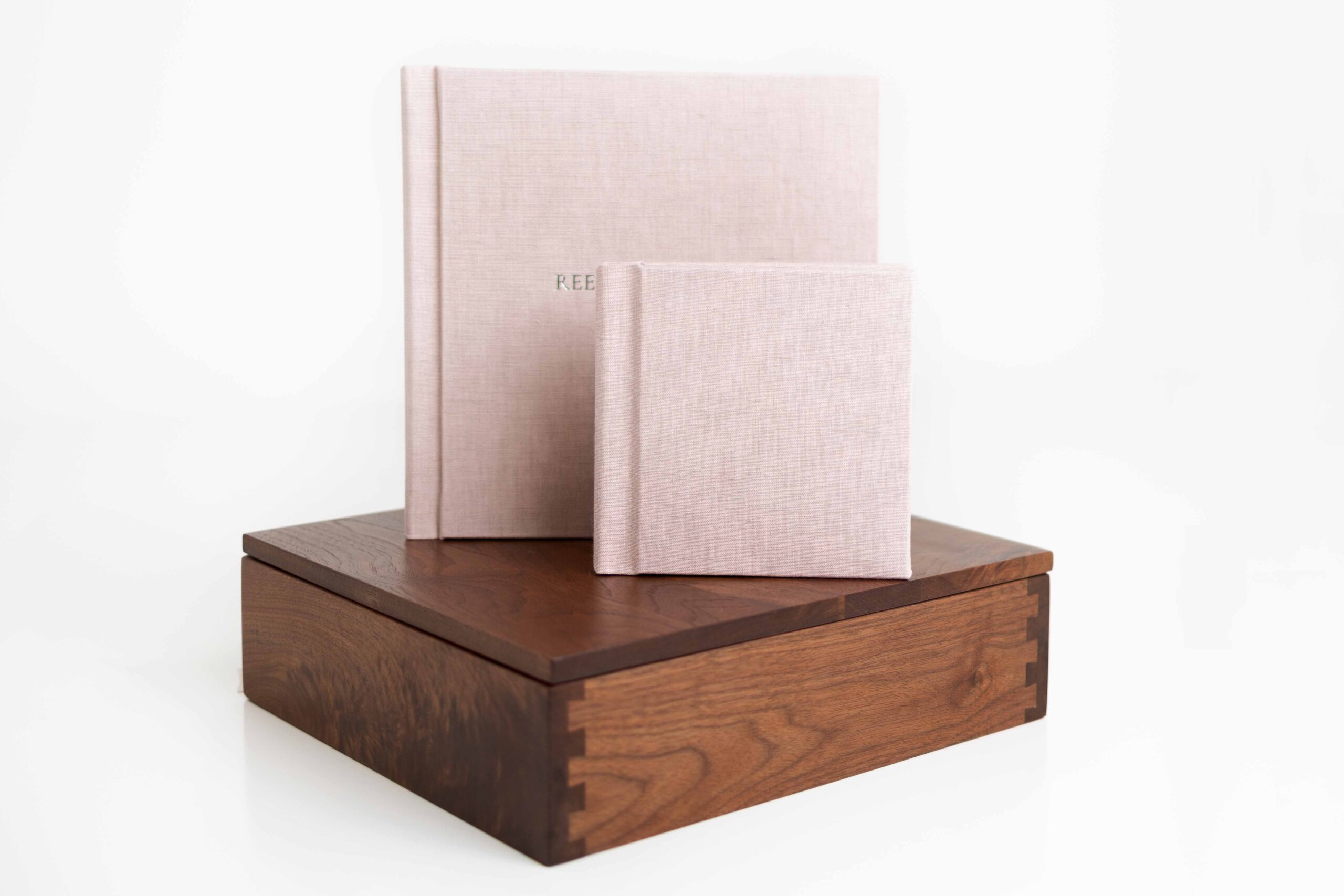 Pink album and mini album on top of wood box by Flower Mound Newborn Album