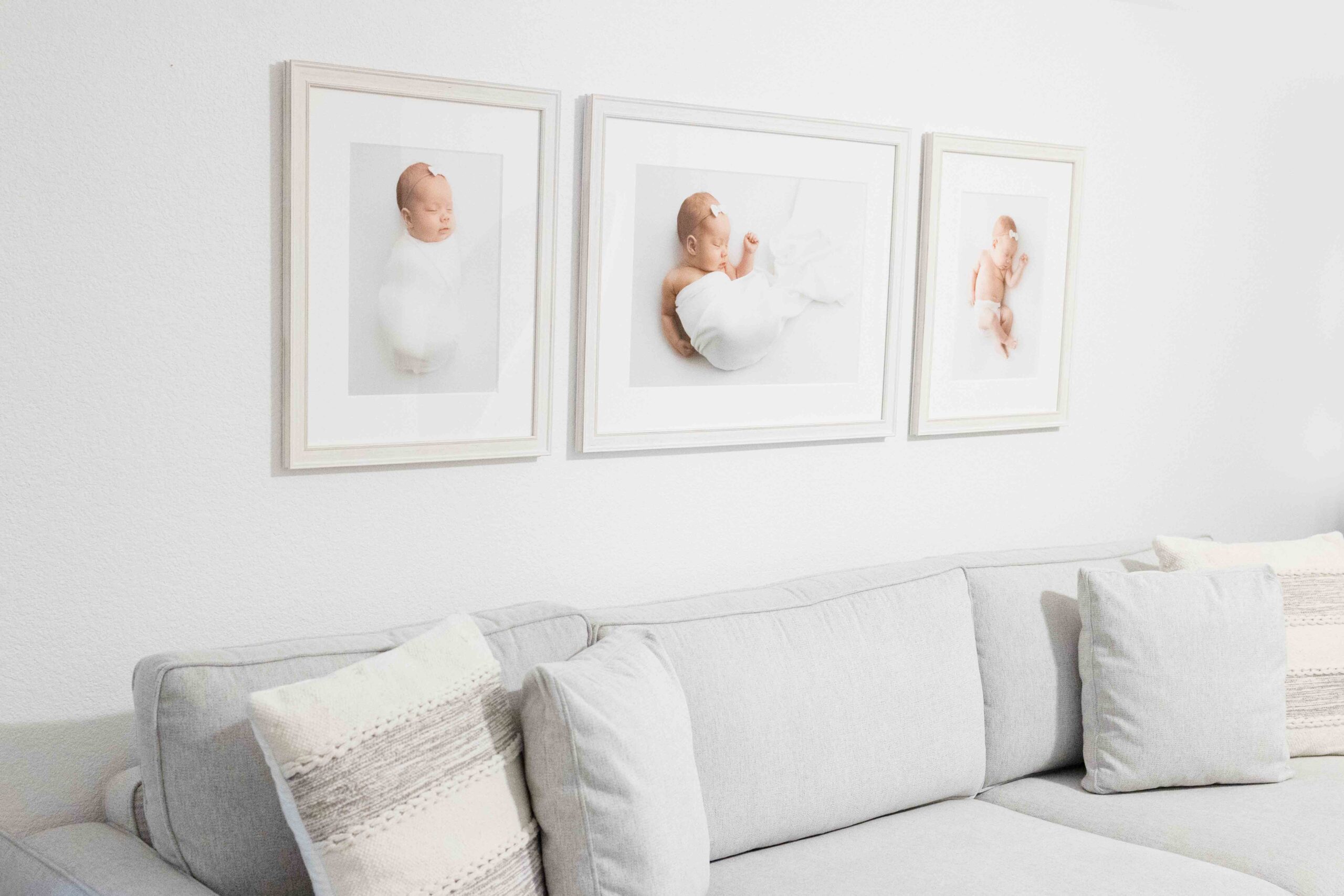 Three framed newborn pictures over a couch for Flower Mound Newborn Wall Art