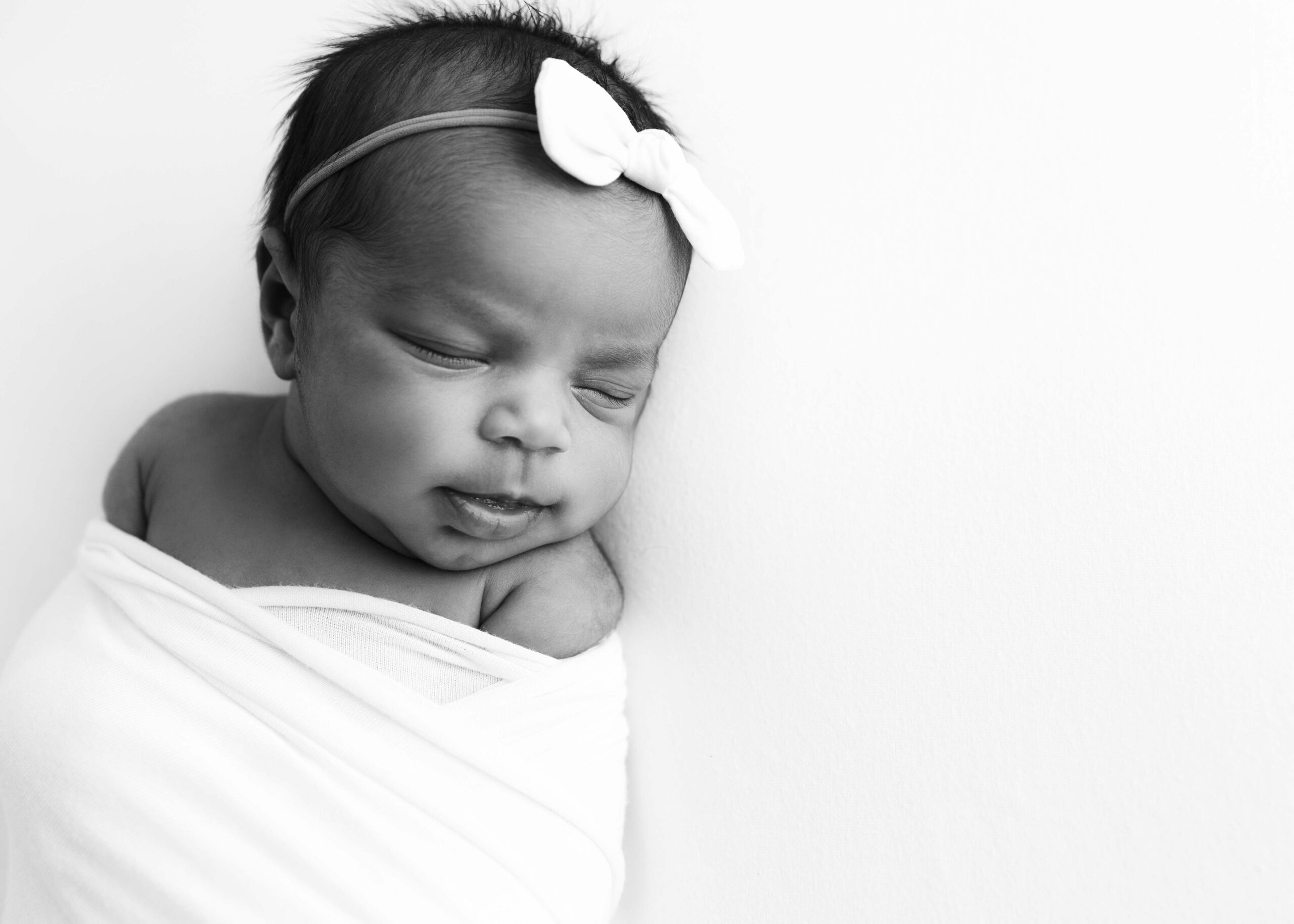 Newborn girl with white bow by DFW Newborn Photography