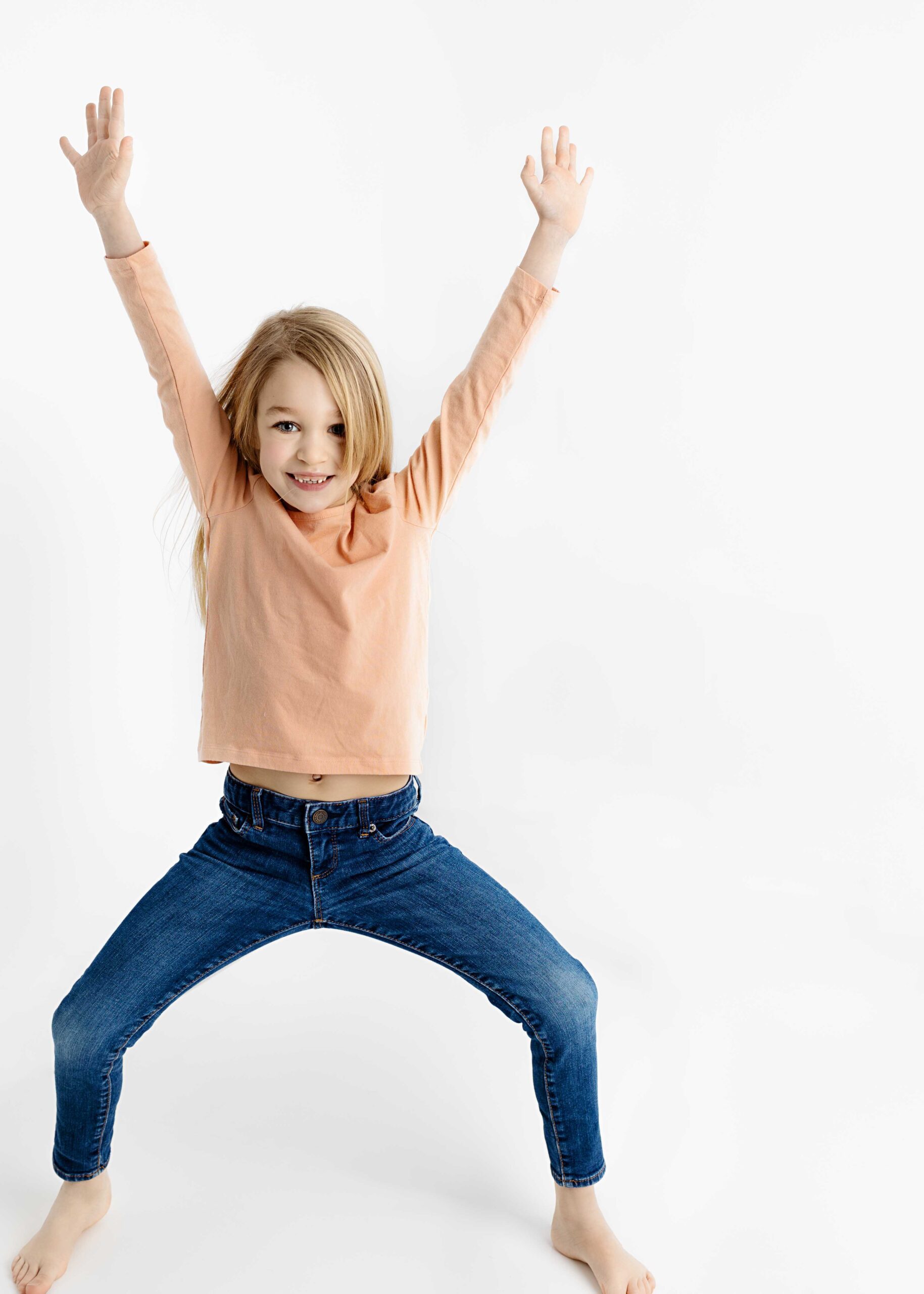 little girl with outstretched legs and arms smiling for the camera