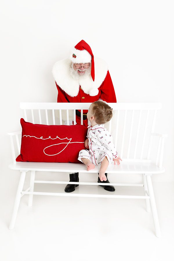 Santa behind a little boy on a bench