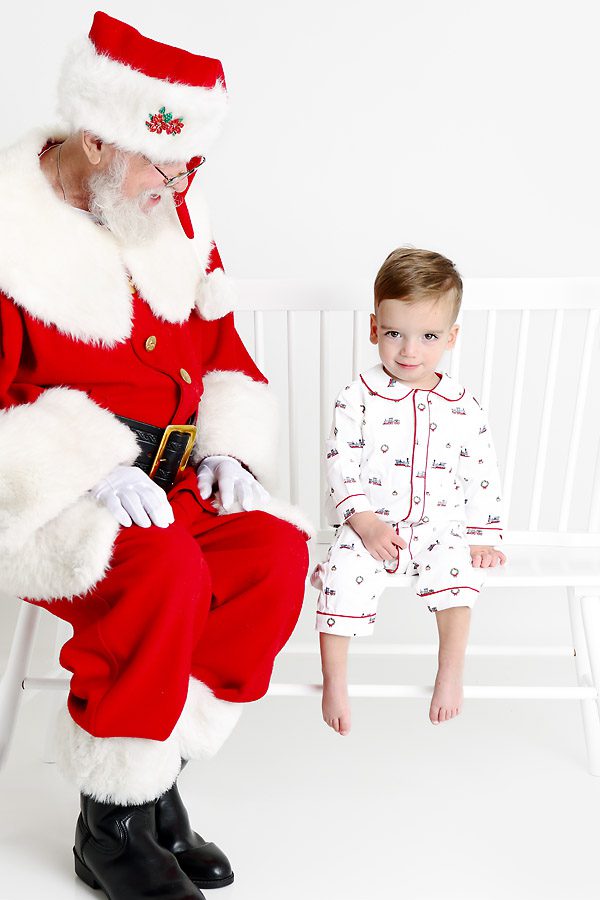 Santa sitting on a bench looking at a little boy