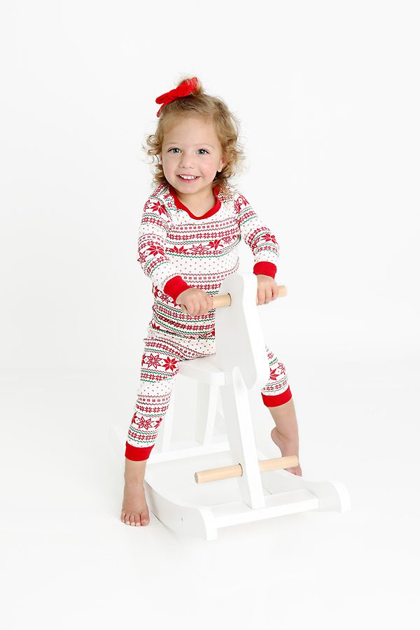 Little girl in Christmas pajamas on a rocking horse for pictures with Santa Dallas, TX