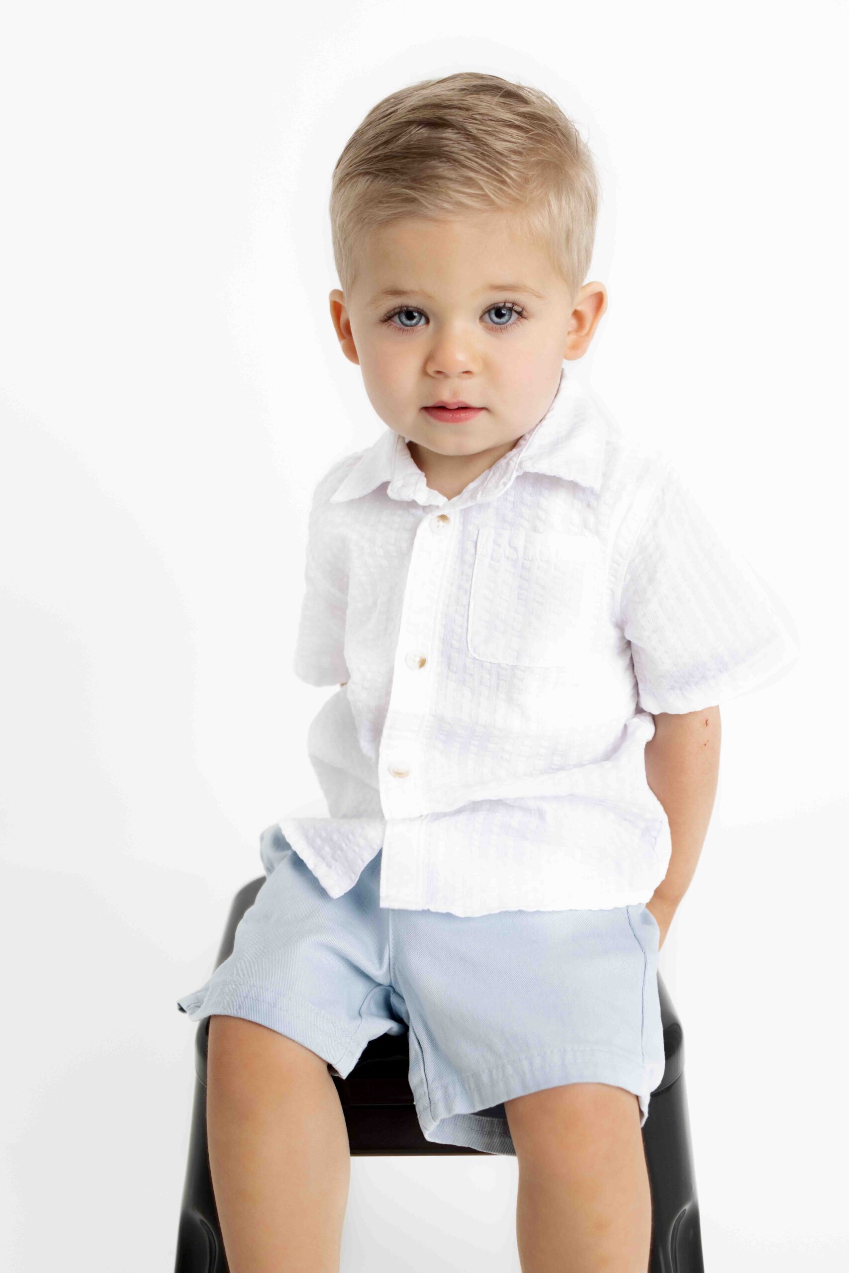 little boy sitting on a stool looking at the camera