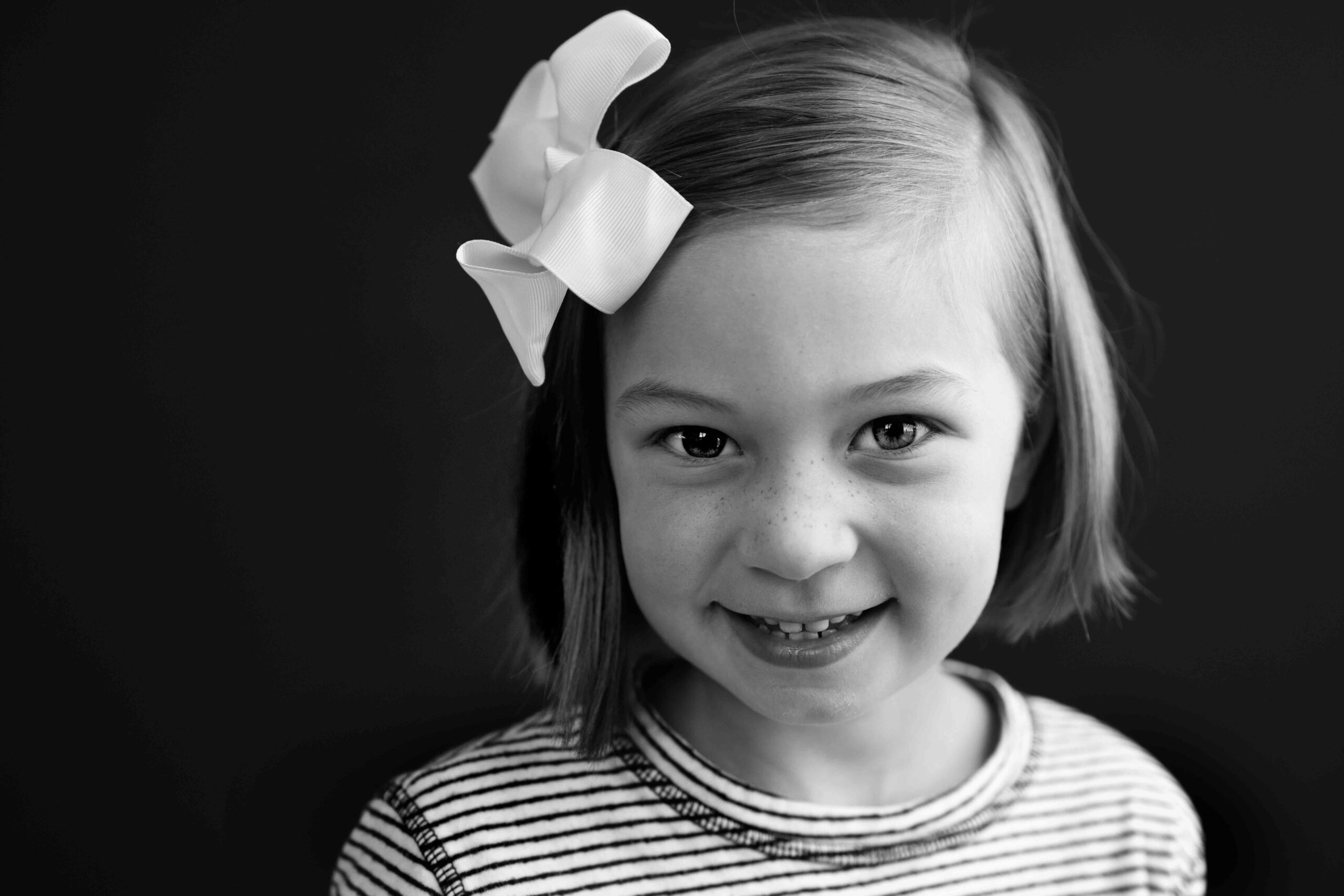 black and white portrait of little girl with white bow in her hair