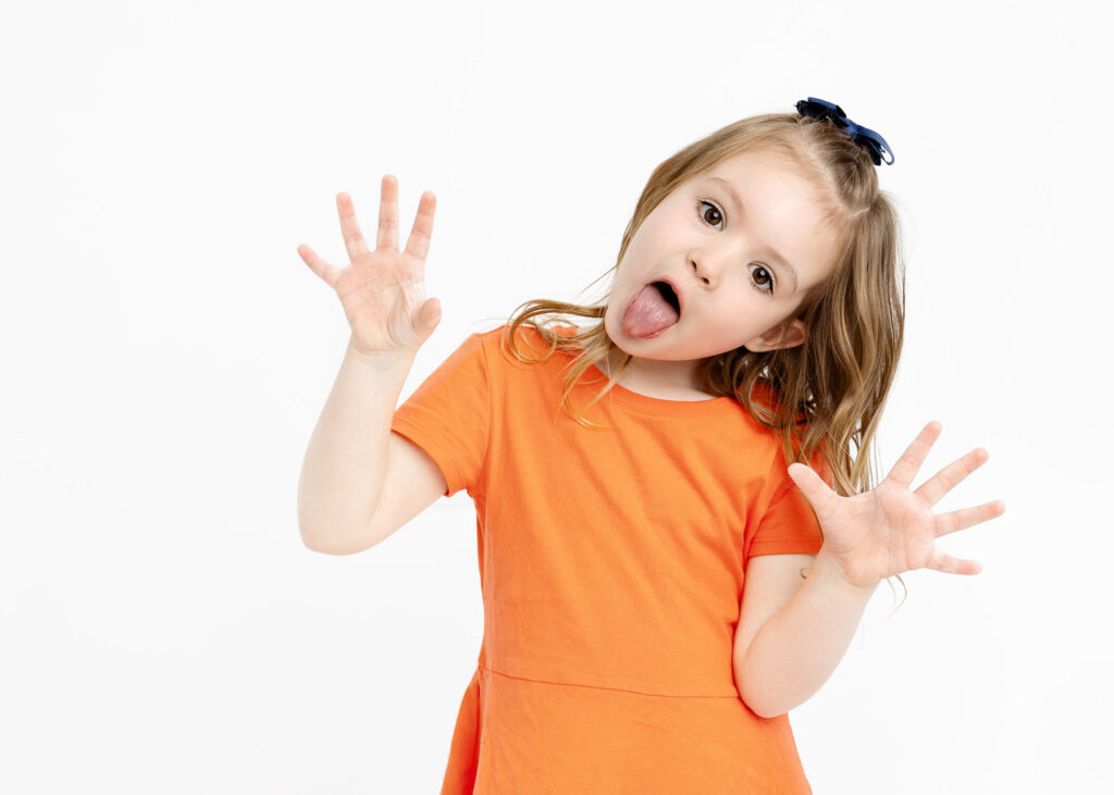 Little girl in orange dress sticking her tongue out 