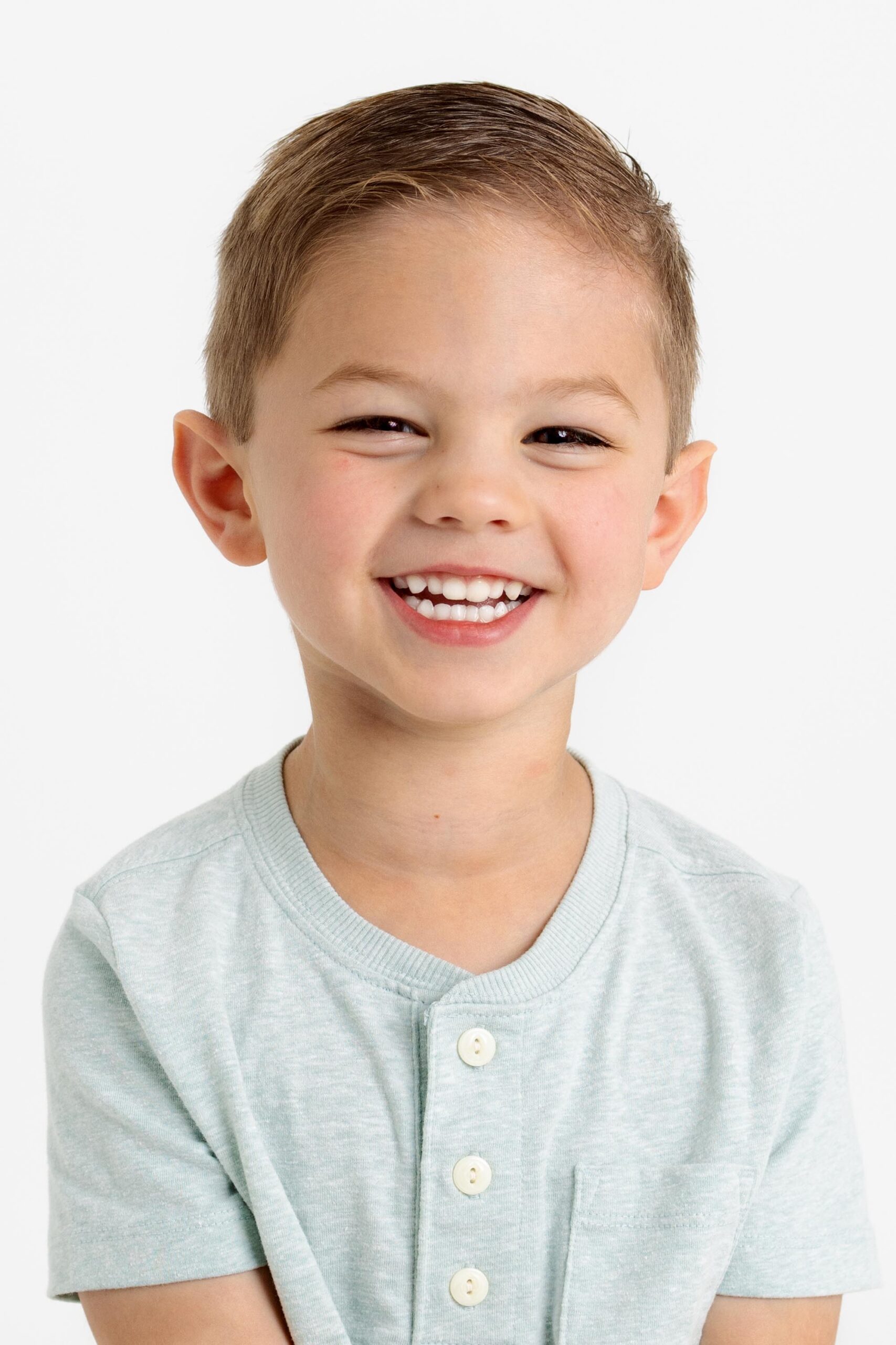 Little boy with blue henley on smiling at camera