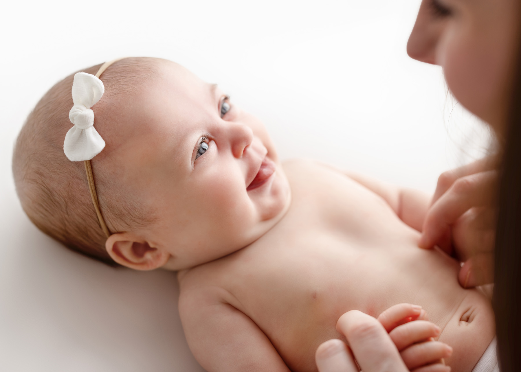 Newborn baby girl smiling up at her mom